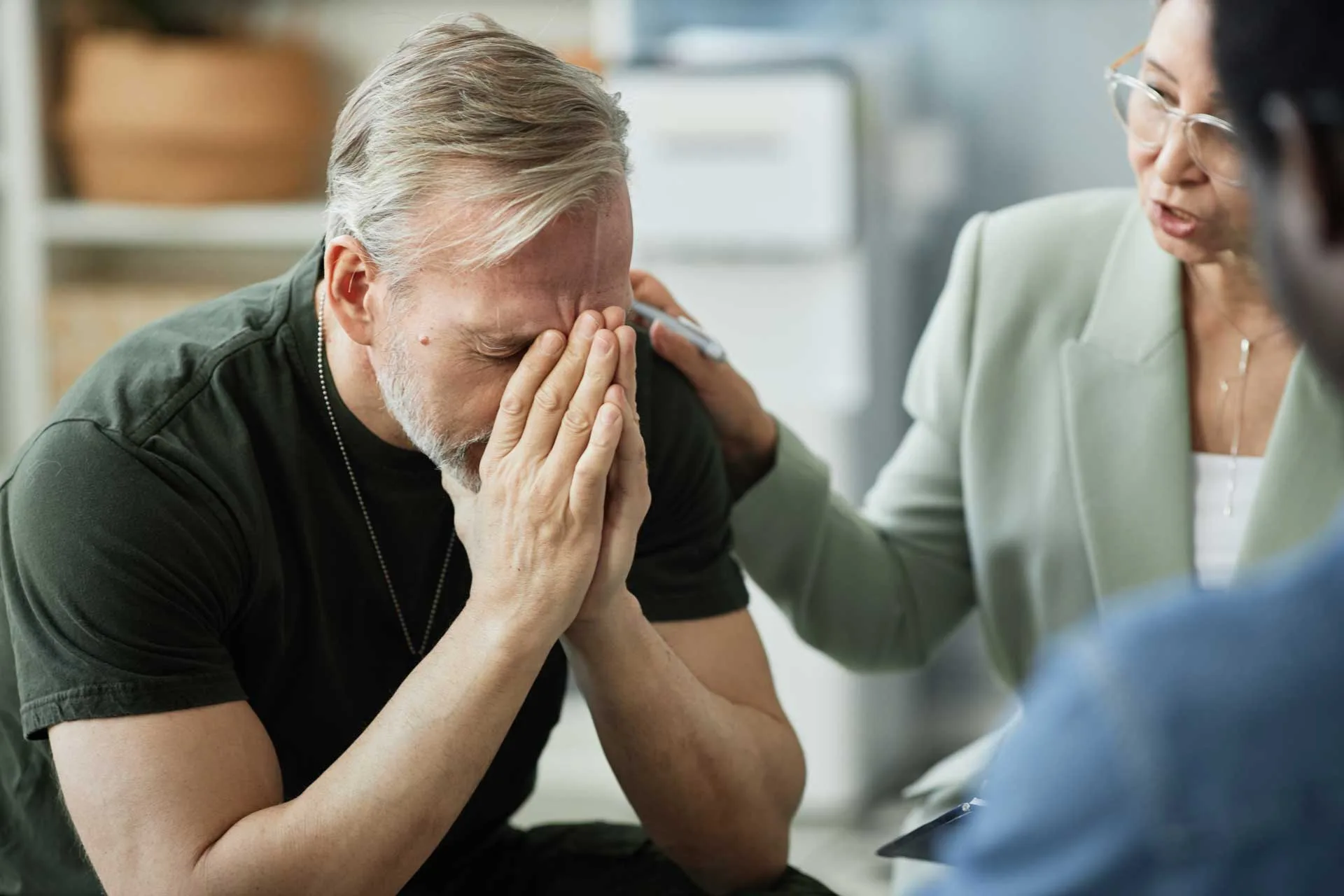 Man covers his face during a grief counseling session.