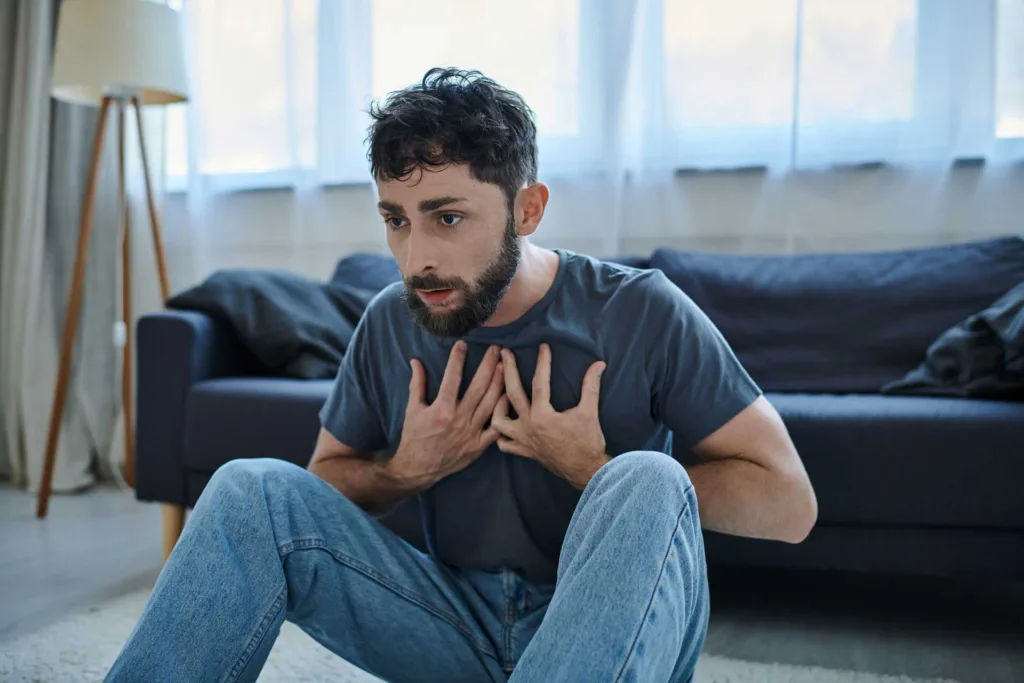 a man sits on the floor as he tries to breath while suffering a panic attack
