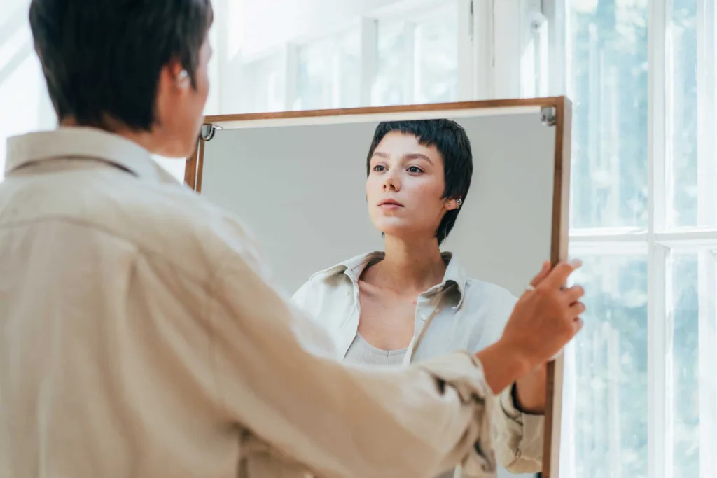 Woman looks at herself in the mirror as she struggles with her body image.